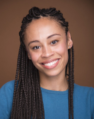 Development Fellow Mykel Nairne is an African-American woman with her hair in long, dark brown braids. She is wearing a turquoise top and is smiling at the camera.
